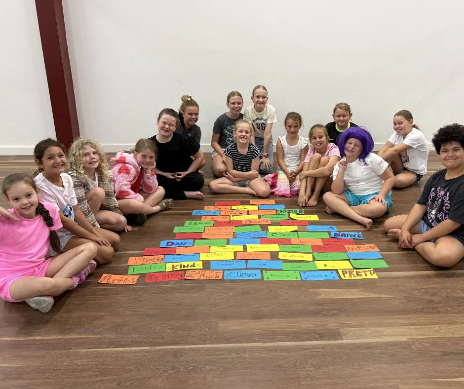 Girls sitting together in a homeschool group activity with colourful affirmation cards on the floor